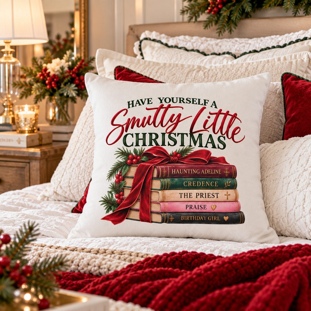 White Smutty Little Christmas romance reader pillow cover displayed on a cozy Christmas bed with cream bedding, red accents, evergreen and warm holiday lighting.