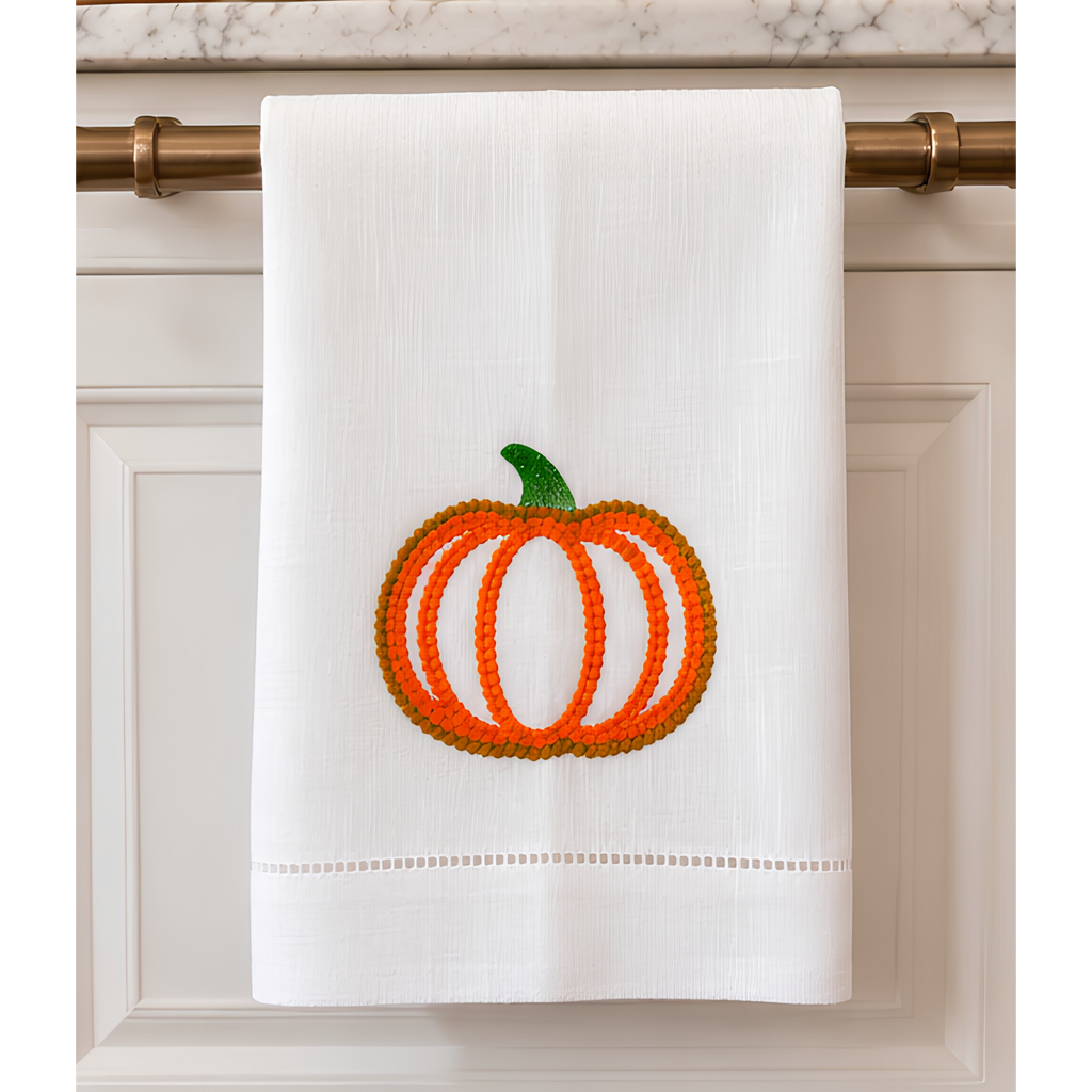 White 14 by 22 linen kitchen towel with textured orange and golden embroidered pumpkin, green stem and decorative hemstitch border.